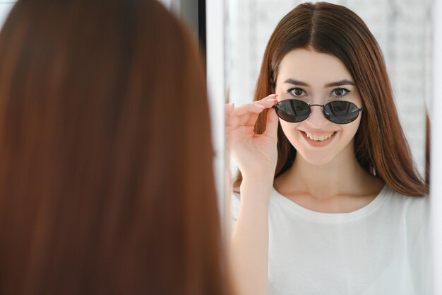 A young woman chooses on sunglasses in an optics store