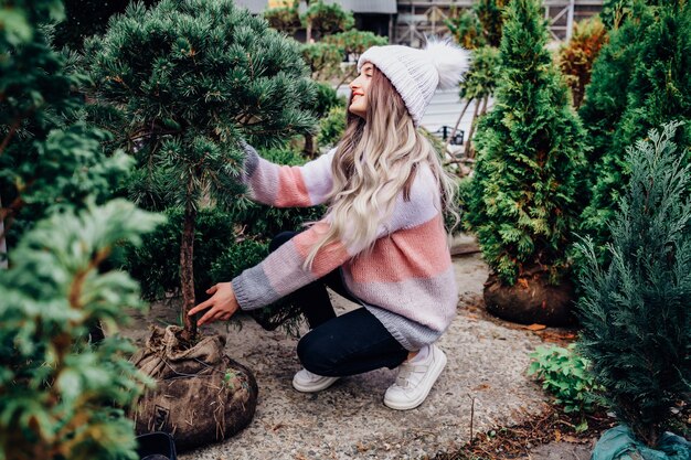 温室でクリスマスツリーを選ぶ若い女性