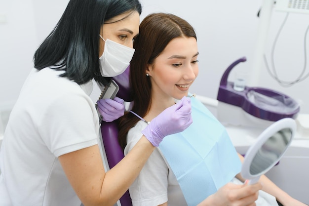 Young woman choosing color of teeth at dentist