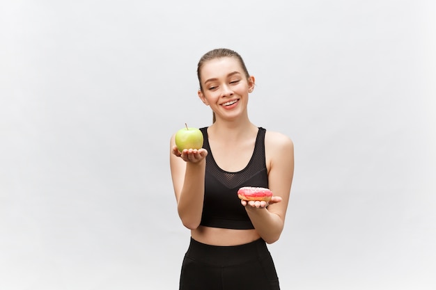 Young woman choosing between dessert and apple   Diet food concept.