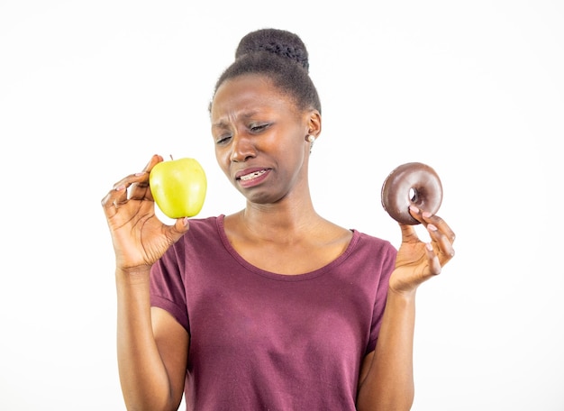 Young woman choosing between healthy food and junk food isolated on white background