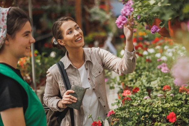 A young woman choosing and shopping for plants and flowers from young female entrepreneur at a garden center.