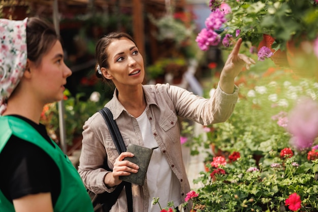 A young woman choosing and shopping for plants and flowers from young female entrepreneur at a garden center.