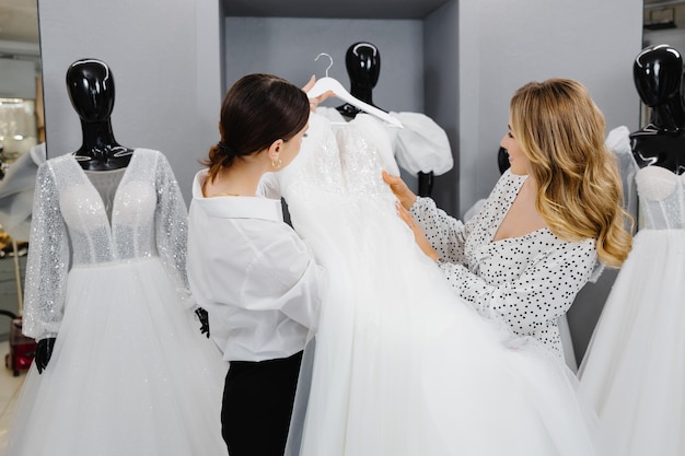 Foto una giovane donna sceglie un vestito da sposa in un salone la sposa è venuta in un salono di abiti da sposa per comprare un vestito