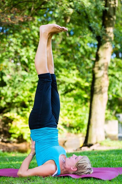 Young woman in city park doing yoga or warming up for exercising