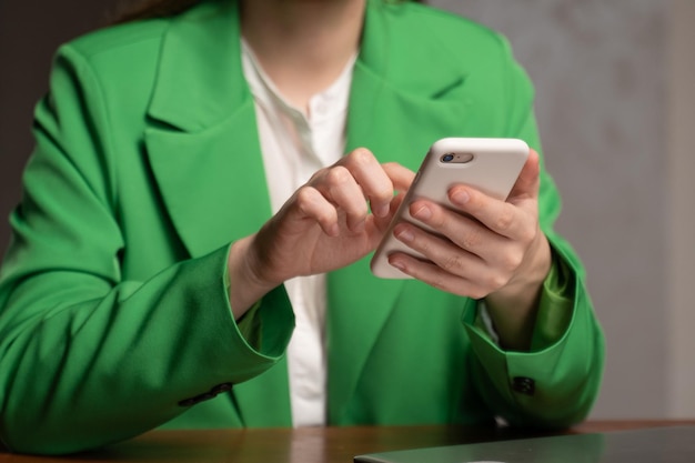 Young woman in classic green jacket checks mail on phone