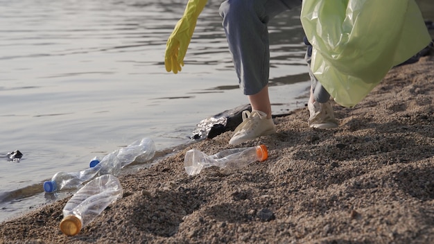 Photo young woman clean up the beach from a trash.