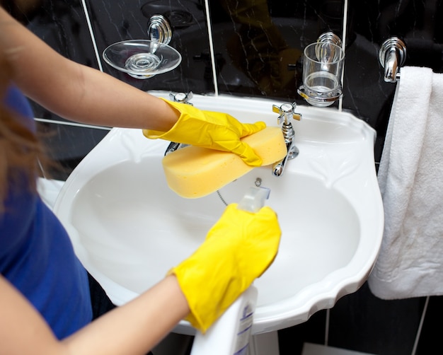 Young woman cleaning a bathroom's sink 