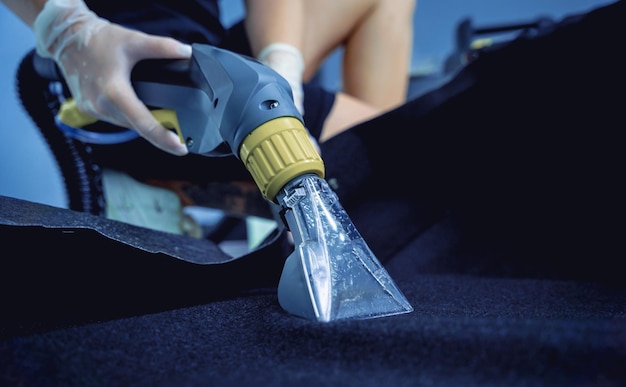 Young woman cleaning the car details with a washing vacuum cleaner