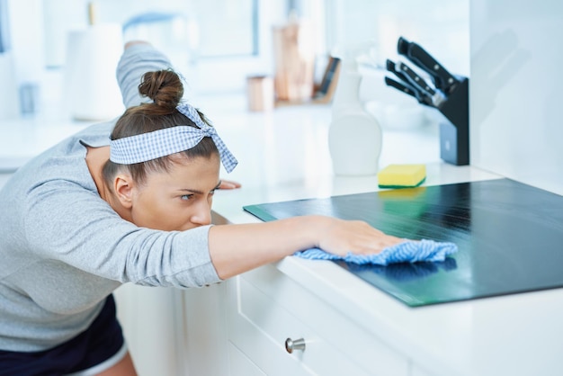 Giovane donna che pulisce lo sporco in cucina