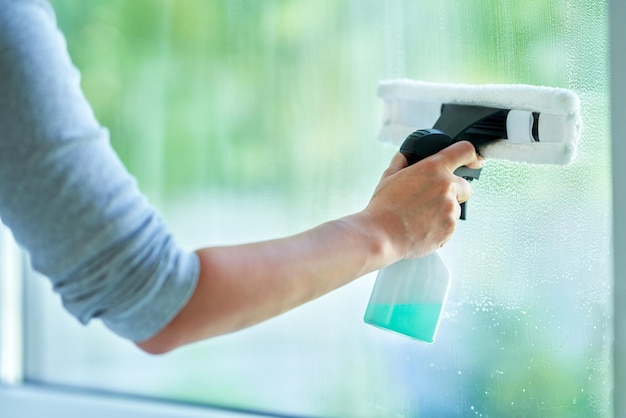 Young woman cleaning window int he kitchen