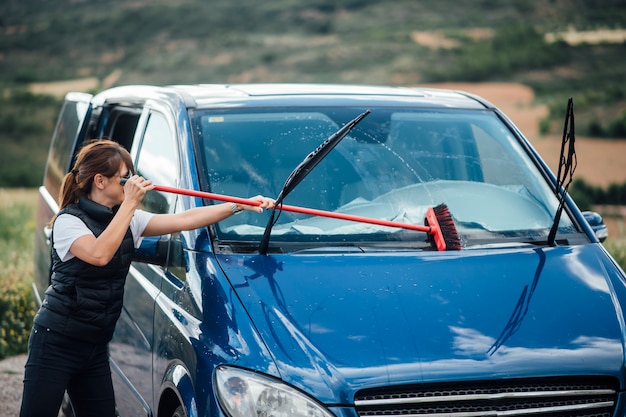 Young woman cleaning the windshield of blue van