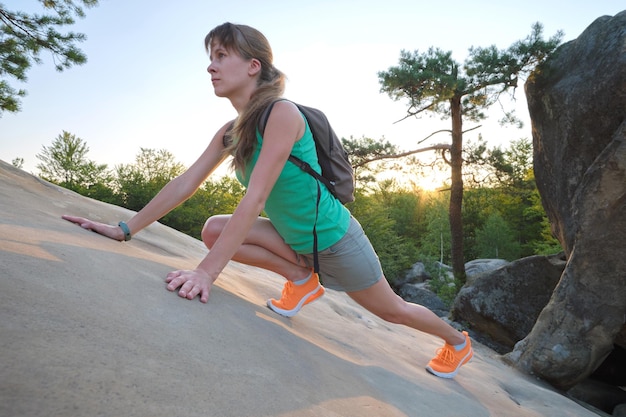 Young woman climbing alone on rocky mountain path Female hiker enjoying difficult challenge on wilderness trail Active way of life concept