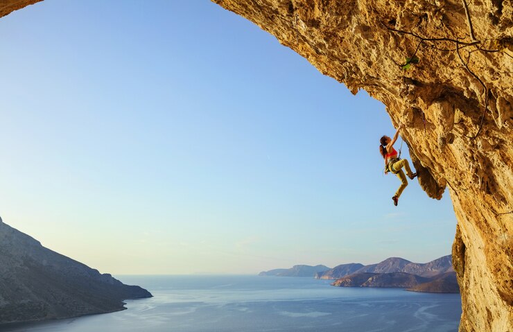 Photo young woman climbing challenging route in cave at sunset, kalymnos island, greece