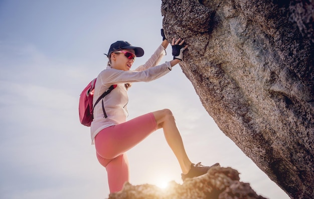 Photo young woman climbs to the top in the mountains near the ocean