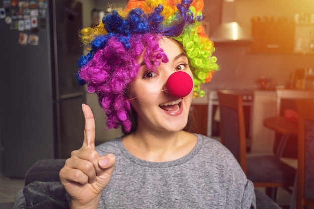 Young woman in a clown wig preparing for holiday