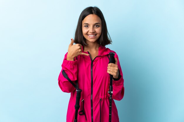 Young woman in a coat with trekking poles