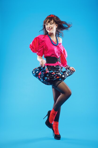 Young woman in colorful oldfashion clothes in pinup style dancing