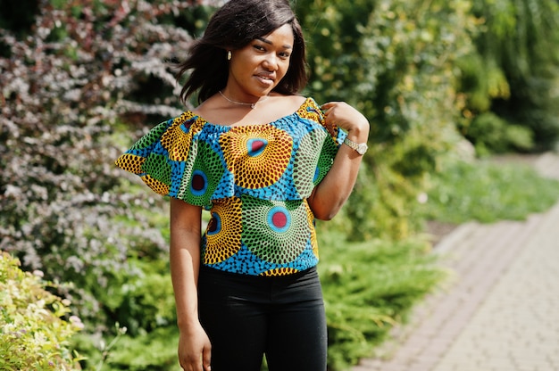 Young woman in coloured shirt and black pants posed outdoor