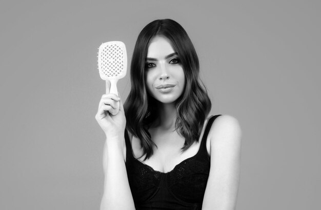 Young woman combing healthy and natural shiny hair isolated on studio Beauty hair care