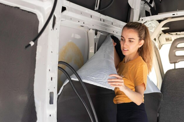 Young woman concentrated looking to the self adhesive rubber\
insulation in a camper van convertion