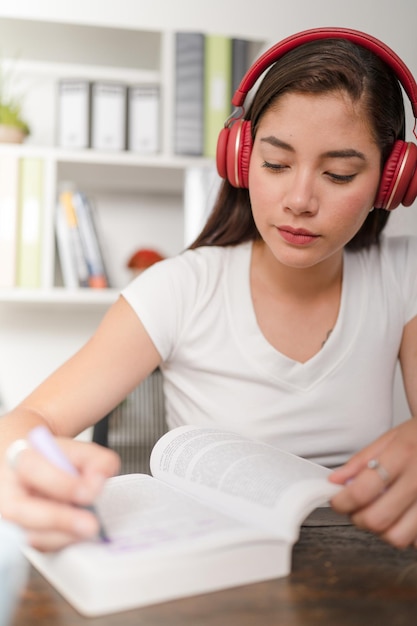 Young woman concentrating listening to music while doing college homework