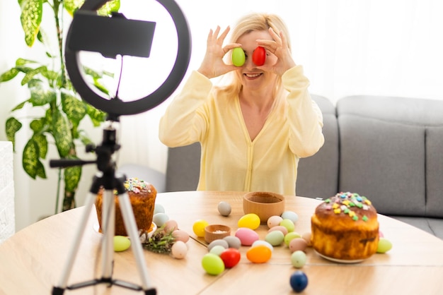 Photo a young woman conducts an online master class on decorating easter eggs. backstage.