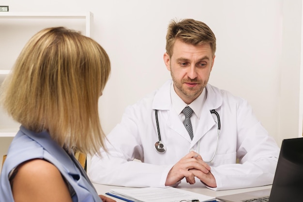 Young woman on a consultation with a male surgeon or therapist in his office Selective focus on the doctor