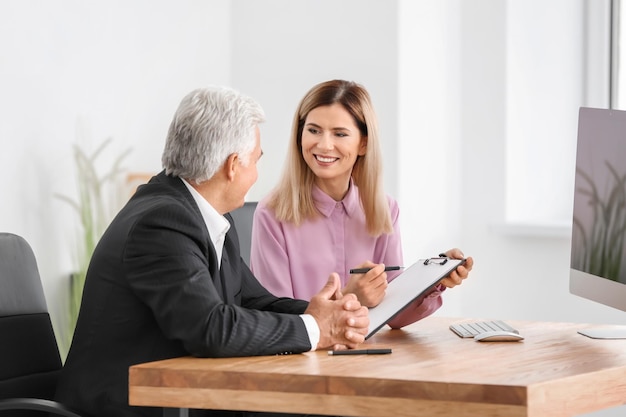 Young woman consulting elderly man in office