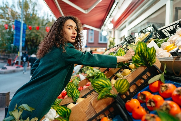 Foto giovane consumatrice che sceglie i prodotti da acquistare presso lo stand del mercato degli agricoltori locali