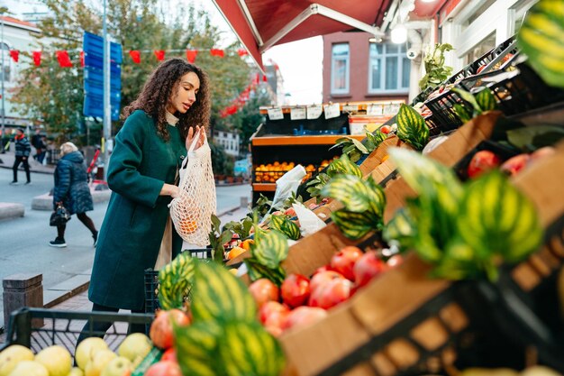 写真 若い女性消費者が地元の農家市場のスタンドで購入する製品を選んでいます