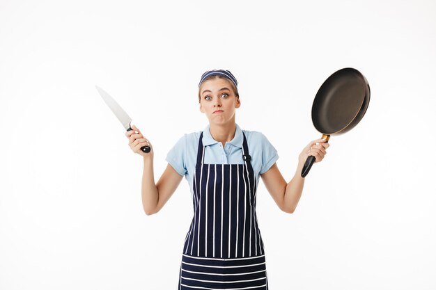 Foto giovane donna cucinare minuziosamente in grembiule a strisce e berretto