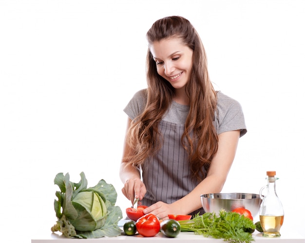 Giovane donna che cucina in cucina. cibo sano - insalata di verdure.