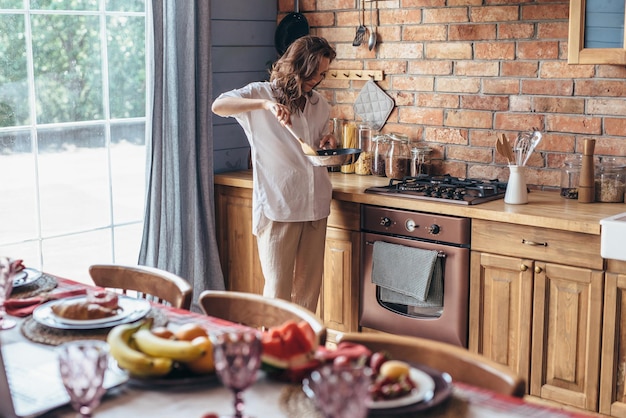 Young woman cooks food in a skillet