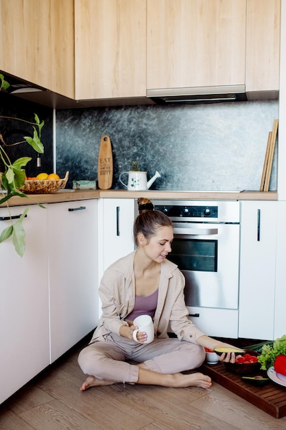 若い女性は台所で料理をし、家でピクニックをします屋内植物の検疫中にビーガン