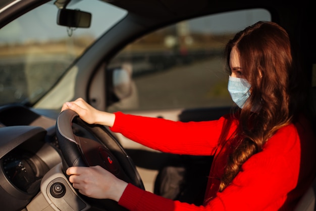 車に座っているコロナウイルスマスクの若い女性