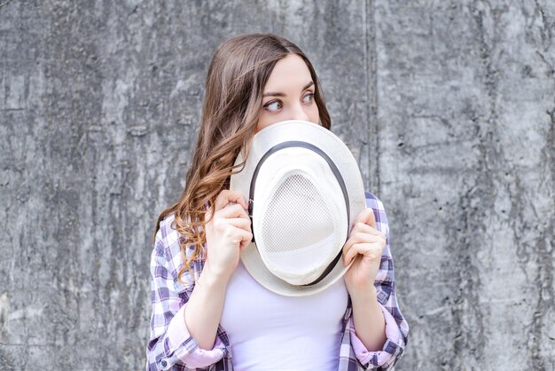 Young woman covering mouth with white hat