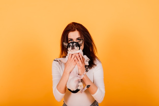 Young woman cuddling chihuahua puppy in studio, isolated