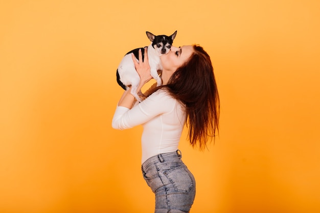 Young woman cuddling chihuahua puppy in studio, isolated