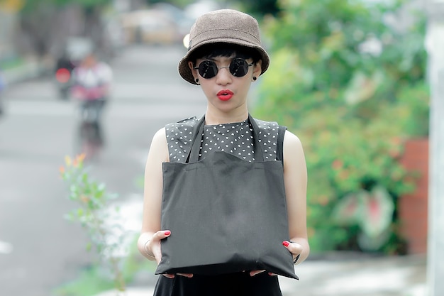 young woman in cute hat showing her sling bag