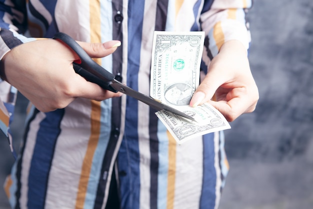 Photo young woman cuts dollar with scissors