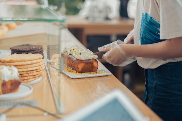 ベーカリーショップでケーキを切る若い女性