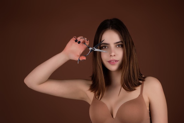 Young woman cutting hair with scissors isolated on studio background beautiful girl about to cut hai