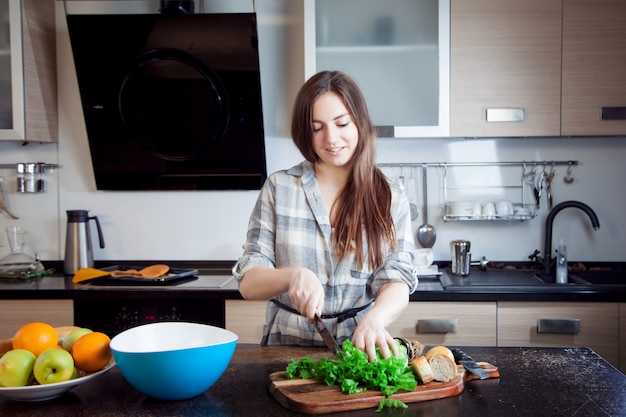 Young woman cutting salad in a kitchen