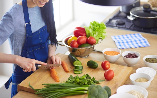 自宅のキッチンで野菜を切る若い女性