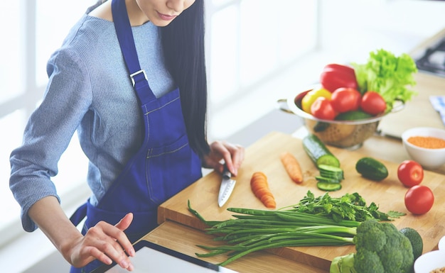 Young woman cutting vegetables in kitchen at home