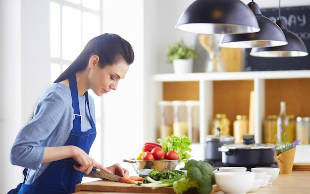 Young woman cutting vegetables in kitchen at home