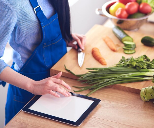 Young woman cutting vegetables in kitchen at home