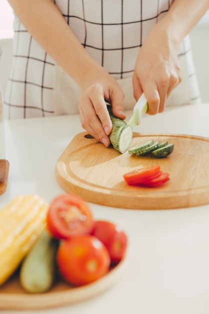 Giovane donna che taglia le verdure in cucina