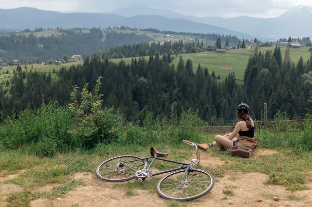 젊은 여성 자전거 타는 사람은 녹색 산길에서 아름다운 전망을 즐깁니다.